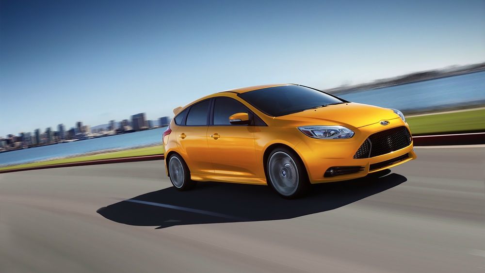 Обои для рабочего стола Желтый автомобиль Ford Focus ST / Форд Фокус СТ едет по дороге