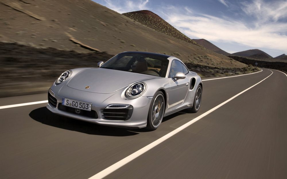 Обои для рабочего стола Серое авто Porsche 911 Turbo S / Спорткар Порш 911 Турбо С едет по дороге у гор на фоне неба