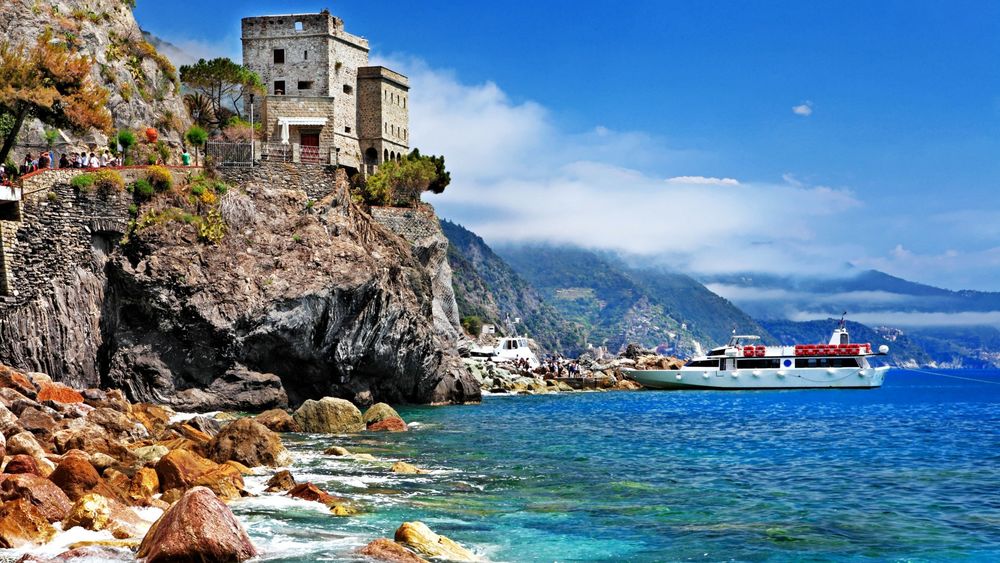 Обои для рабочего стола Яхта причалила к скалистому берегу, на котором расположен старый каменный дом, национальный парк Чинкве-Терре / Cinque Terre, Вернацца, Италия / Vernazza, Italy
