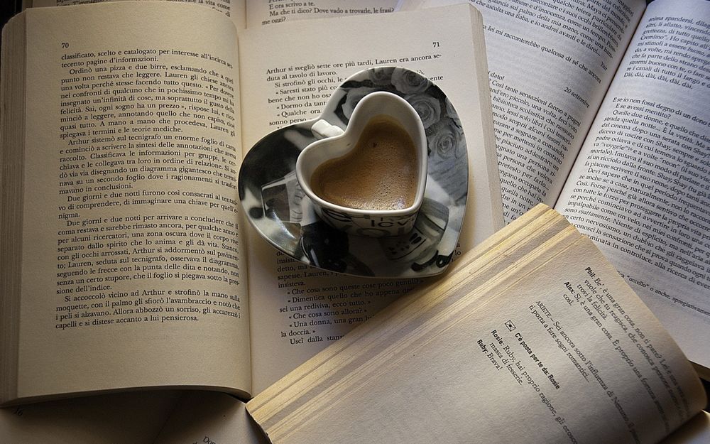 Обои для рабочего стола Чашка кофе в форме сердца стоит на страницах книги