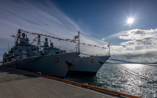 Обои на рабочий стол Военные корабли, стоящие у пирса на фоне неба и яркого света солнца