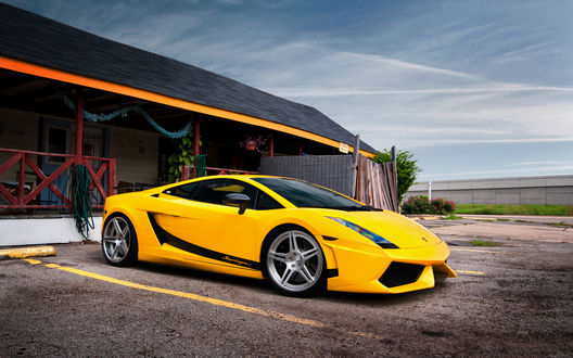 Обои на рабочий стол У небольшого дома припарковалась желтая Lamborghini