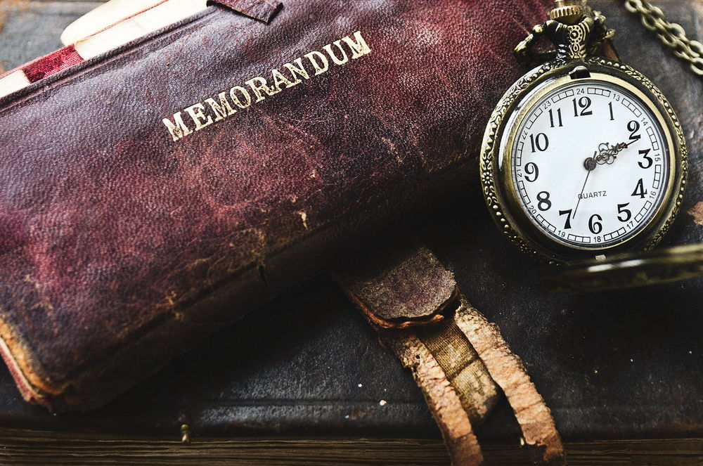 Обои для рабочего стола Карманные часы с металлической открытой крышкой и цепочкой, лежащие возле старинной кожаной книги с надписью MEMORANDUM / Меморандум