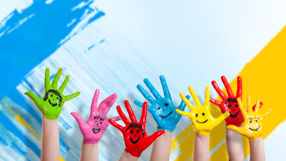 Обои для рабочего стола Детские руки с нарисованными на них смайлами в разноцветной краске