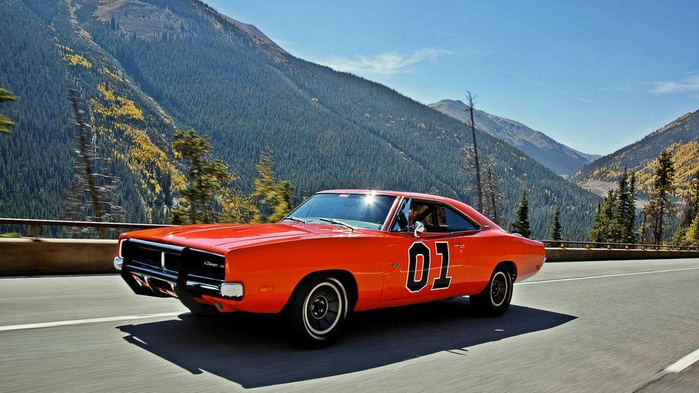 Обои для рабочего стола Автомобиль Chrysler General Lee / Крайслер Дженерал Ли, кирпичного цвета с номером 01 на дверце едет по дороге в горной местности