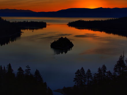 Обои на рабочий стол Небольшой островок по середине реки, берега которой покрыты густым лесом