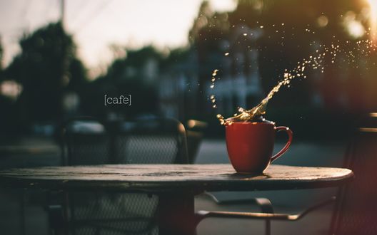 Обои на рабочий стол Брызги кофе в красной чашке на столе (Cafe / Кафе)