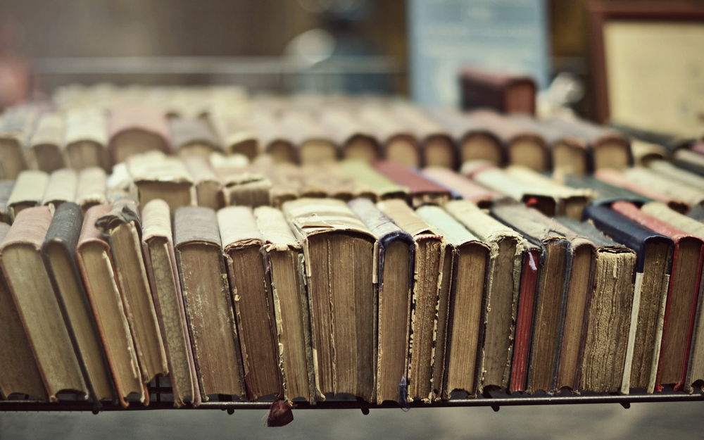 Обои для рабочего стола Старые книги в потрепанных переплетах стоят на столе