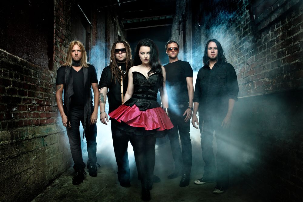 Обои для рабочего стола Музыкальная группа Evanescence, солистка Amy Lee / Эми Ли, мужчины с девушкой стоят возле кирпичных стен домов, позади них темнота и туман