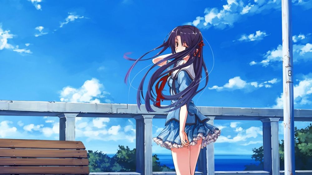 Обои для рабочего стола Девушка в школьной форме стоит рядом с забором придерживает рукой длинные темные волосы и оборачивается на фоне голубого неба и синего моря