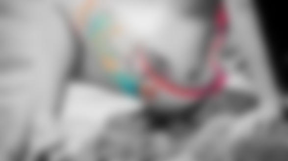 Обои на рабочий стол Девушка с цветной татуировкой сидит на камнях