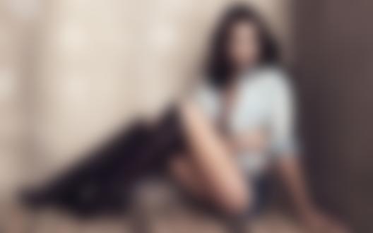 Обои на рабочий стол Модель Irina Shayk / Ирина Шейк в черных ботфортах, кототких джинсовых шортах и расстегнутой рубашке, сидит в углу у стены