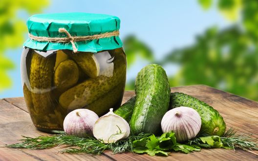 Обои на рабочий стол Банка с маринованными огурцами, рядом с банкой лежат свежие огурцы, головки чеснока и зелень, необходимая для засолки