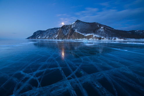 Обои на рабочий стол Ледяные узоры на озере Байкал, Россия / Baikal, Russia на фоне горного образования и заката солнца на синем небе с небольшой облачностью, фотография Алексея Харитонова