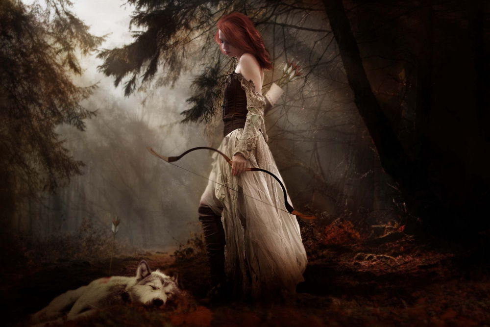 Обои для рабочего стола Рыжая девушка с луком в руках стоит в лесу рядом с застреленным, ее же стрелой, волком