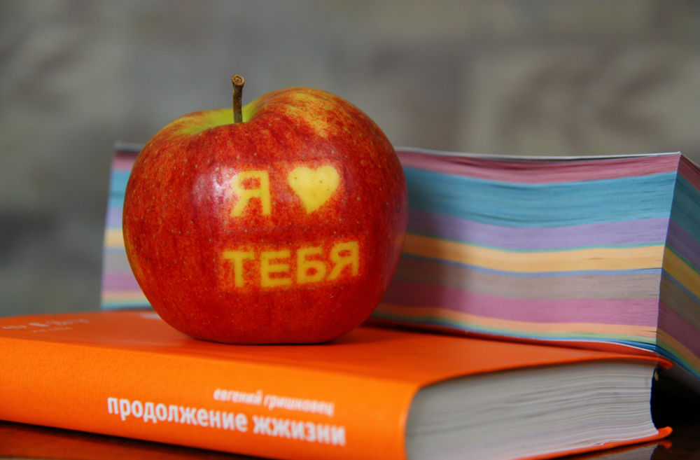 Обои для рабочего стола Красное яблоко с желтой надписью Я люблю тебя лежит на книге Евгения Гришковца Продолжение жизни