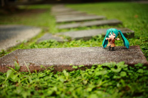 Обои на рабочий стол Маленькая фигурка Vocaloid Hatsune Miku / Вокалоид Хацуне Мику в плаще стоит на дорожке под дождем