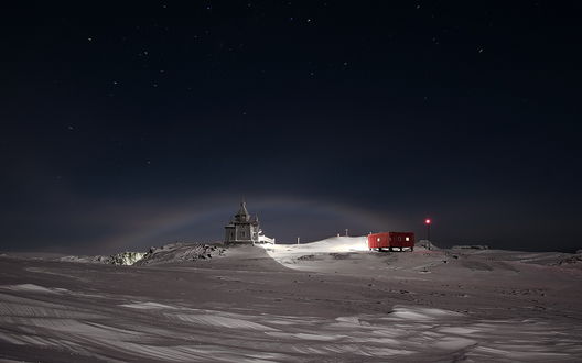 Обои на рабочий стол Лунная (ночная) радуга в небе Антарктики / Antarctica, над стоящей на окраине полярного поселка церкви, фотография Руслана Елисеева