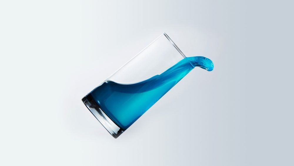 Обои для рабочего стола Падающий стакан с голубой жидкостью
