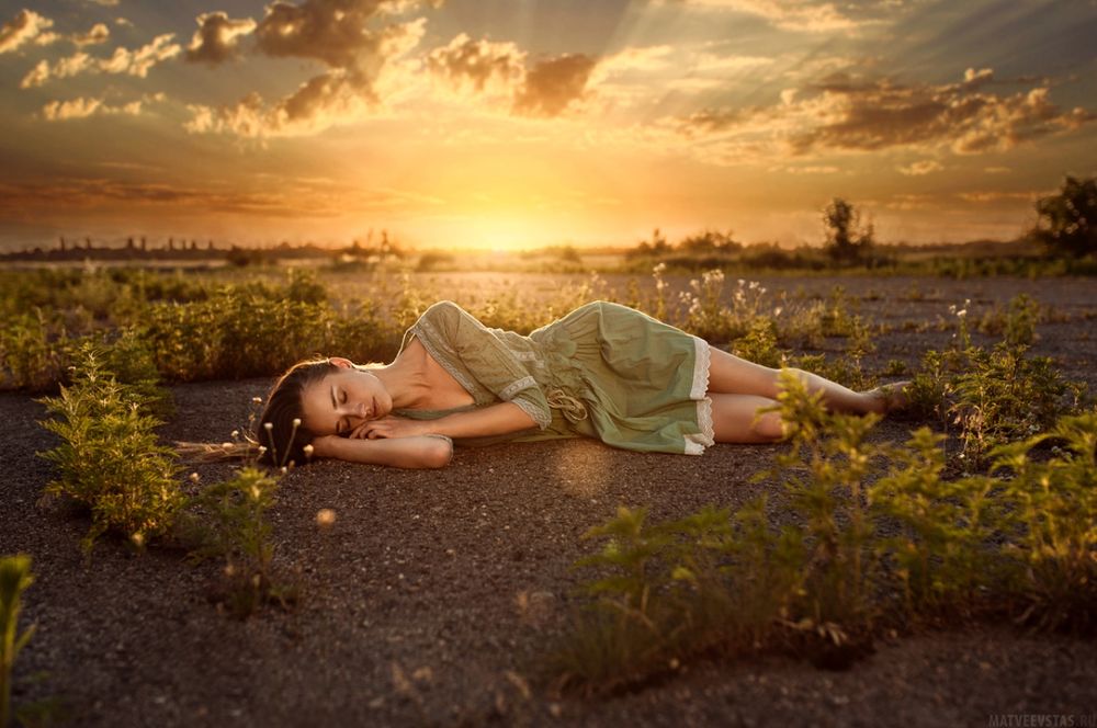 Обои для рабочего стола Девушка лежит на земле на фоне заката