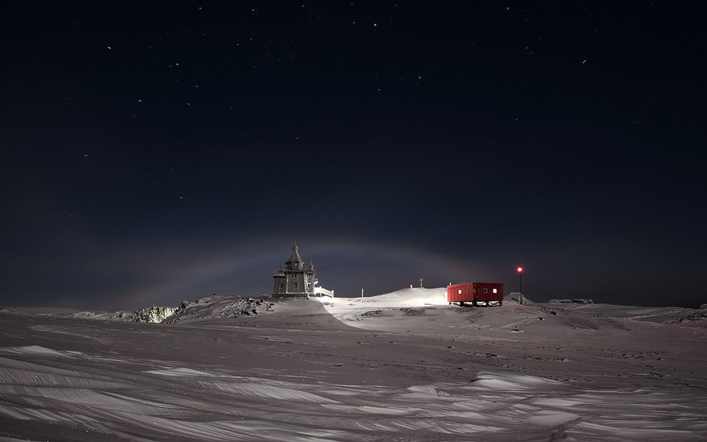 Обои для рабочего стола Лунная (ночная) радуга в небе Антарктики / Antarctica, над стоящей на окраине полярного поселка церкви, фотография Руслана Елисеева