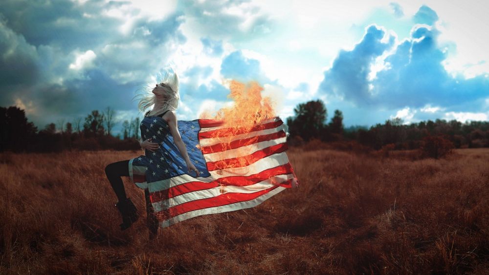 Обои для рабочего стола Девушка одета в американский флаг, который горит