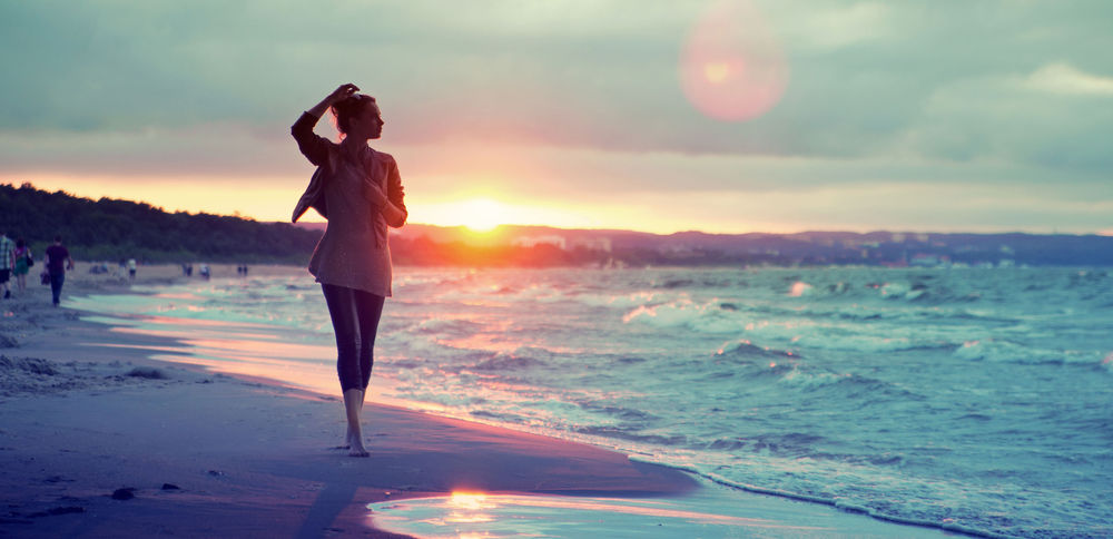 Обои для рабочего стола Девушка гуляет по побережью моря во время заката