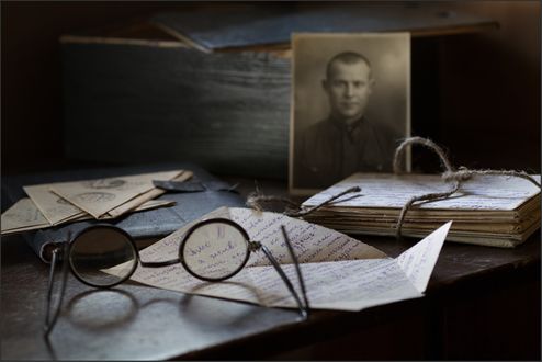 Обои на рабочий стол На столе лежат старые письма, блокнот и очки, на заднем фоне фотография мужчины в военной форме