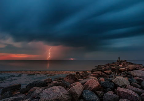 Обои на рабочий стол Неширокий каменный пирс, уходящий в море на фоне темных грозовых туч на небе и сверкающих молний, фотография Tamara Petrejcva