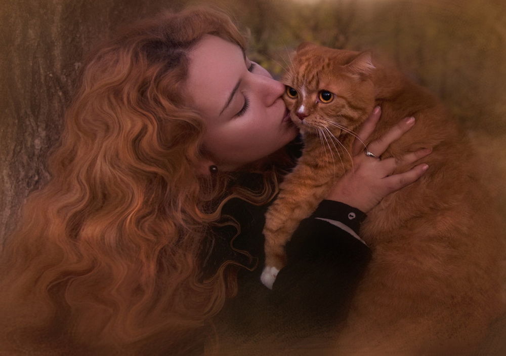 Обои для рабочего стола Красивая девушка с пышной копной рыжих волос, стоящая возле дерева, нежно целует домашнего кота такого же окраса как и ее волосы, находящегося у нее на руках, фотография Татьяны Гаврилович