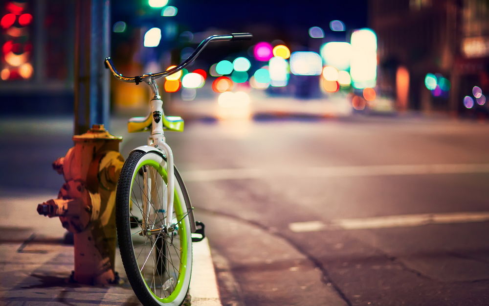 Обои для рабочего стола Ночной город, на улице которого стоит велосипед