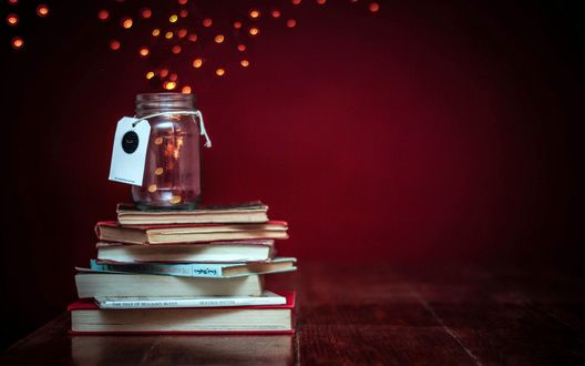 Обои на рабочий стол Из стеклянной банки, стоящей на стопке книг, вылетают огоньки