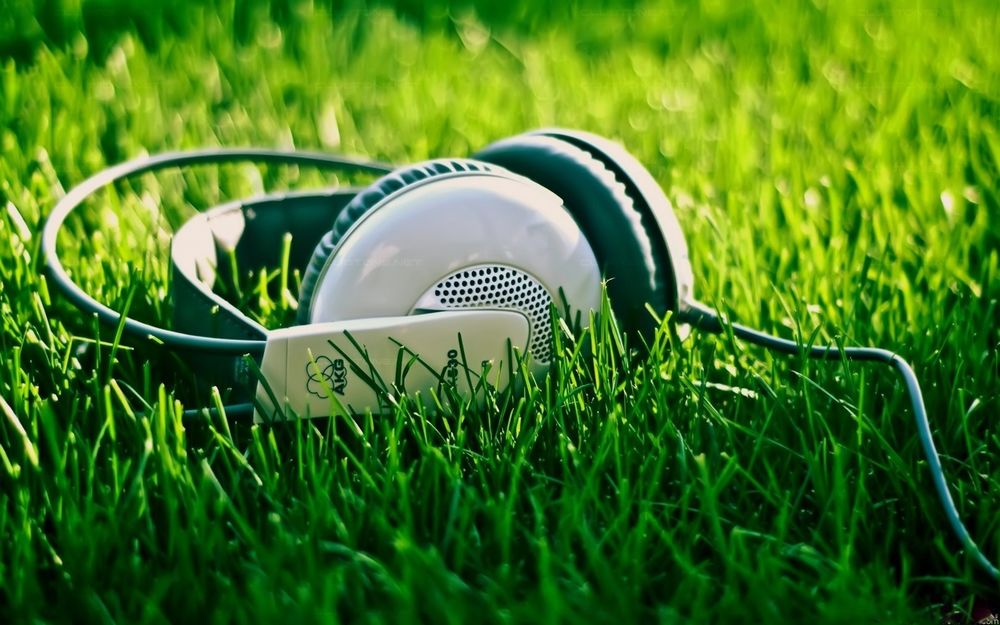 Обои для рабочего стола Наушники фирмы AKG лежат в траве