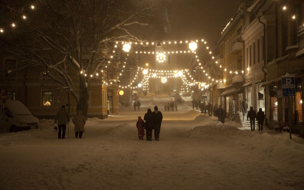 Обои для рабочего стола Люди идут по зимней улице, освещаемой фонарями