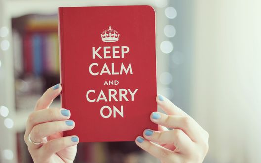Обои на рабочий стол Руки девушки держут в руках книгу с надписью KEEP CALM AND CARRY ON / СОХРАНЯТЬ СПОКОЙСТВИЕ И ВЕСТИ