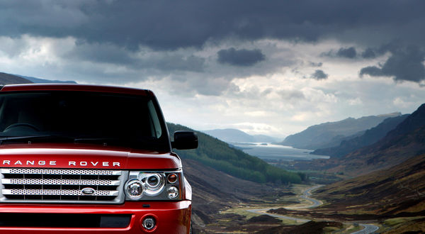 Обои на рабочий стол Автомобиль Range Rover Sport красного цвета, на фоне гор и облаков в небе