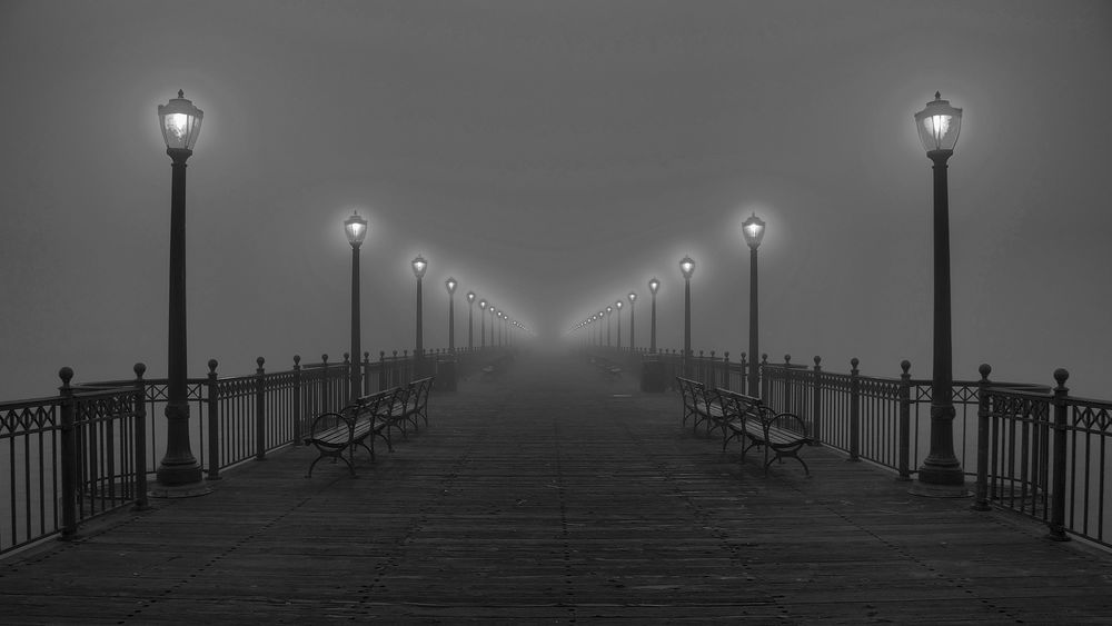 Обои для рабочего стола Бесконечный ряд фонарей на мосту, освещающих туманную мглу