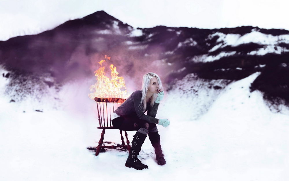 Обои для рабочего стола Девушка сидит на горящем стуле, стоящим на снегу