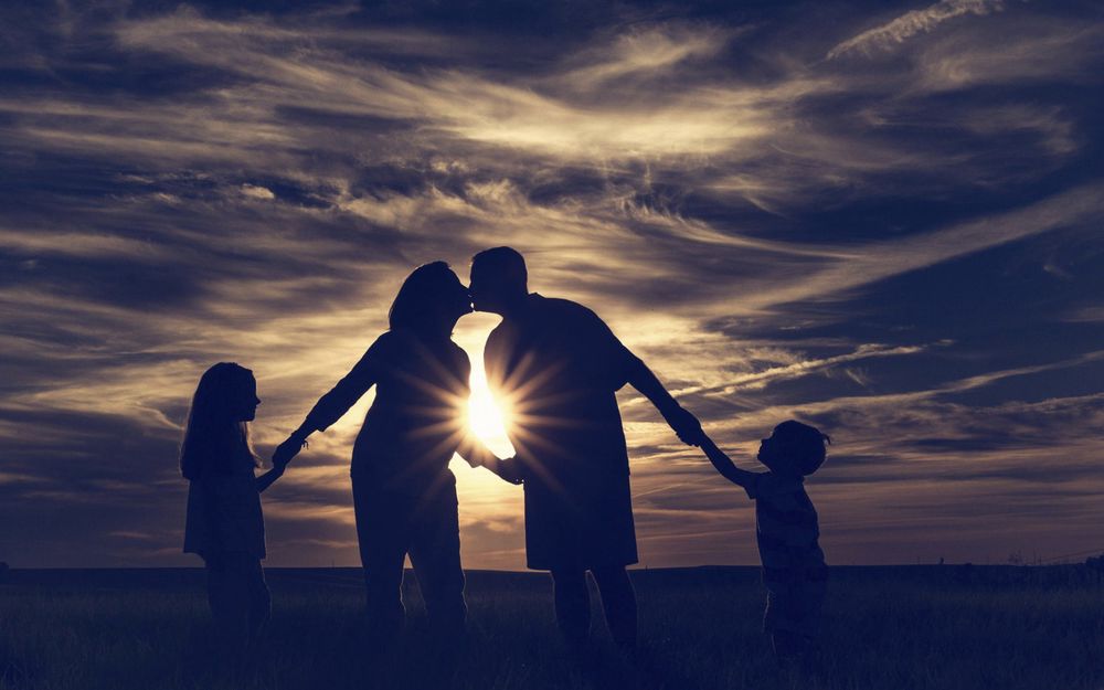 Обои Семейная пара с детьми на фоне красивого неба на закате на рабочий стол