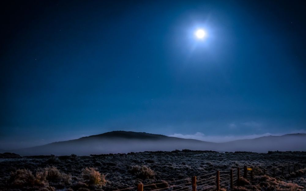 Обои для рабочего стола Горы, у подножия которых клубится туман, на фоне синего ночного неба и полной луны