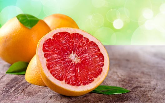 Обои на рабочий стол Разрезанный грейпфрут лежит на зеленом фоне