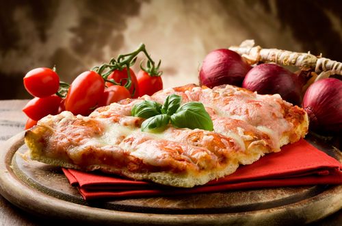 Обои на рабочий стол Кусок пиццы рядом с помидорами и луком