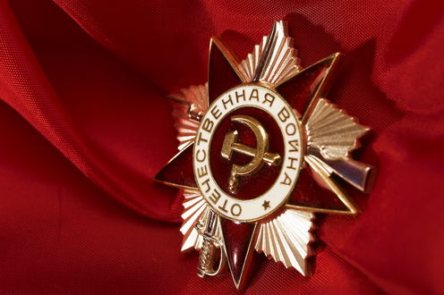 Обои на рабочий стол Значок Отечественная война лежит на красной ткани