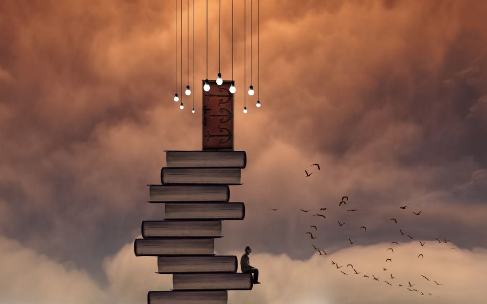 Обои для рабочего стола Мужчина сидит на стопке книг, над которой нависают лампочки, глядя на пролетающую рядом стаю птиц