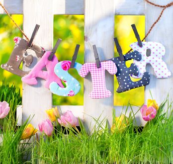 Обои на рабочий стол Надпись Easter / Пасха из букв, висящих на прищепках, под забором растут тюльпаны