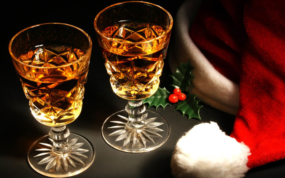 Обои для рабочего стола Два бокала шампанского и колпак Санта Клауса на черном столе