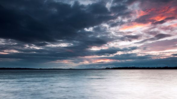 Обои на рабочий стол Темные тучи уходящие за горизонт на море