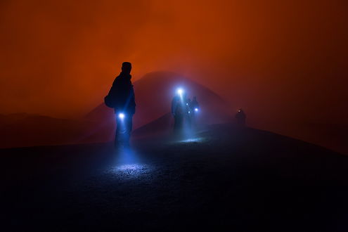 Обои на рабочий стол Люди с электрическими фонариками, идущие по горному склону на фоне ночного неба