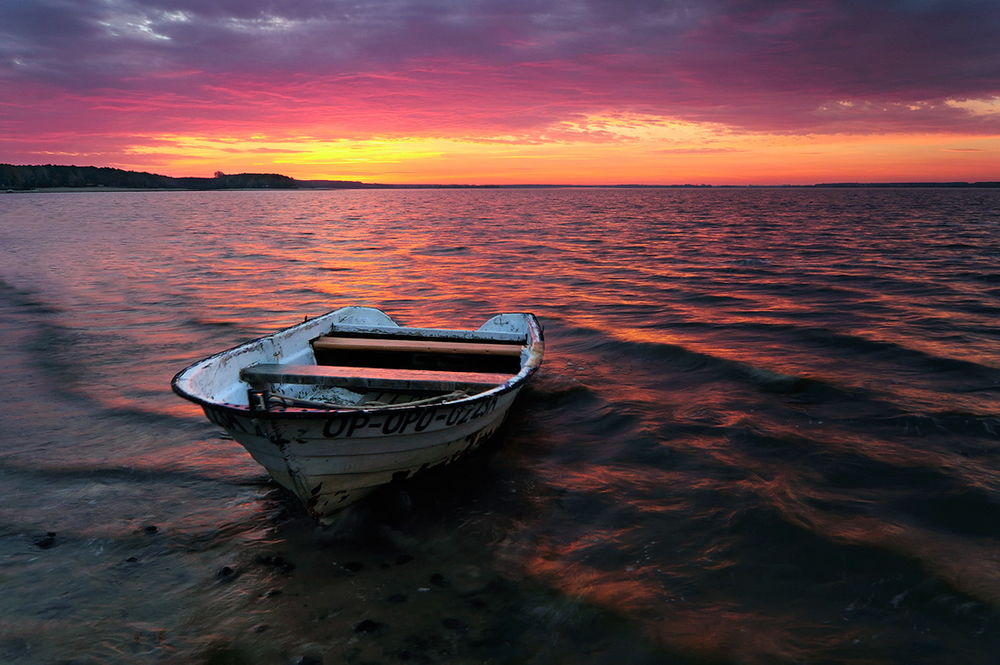 Обои для рабочего стола Деревянная лодка, стоящая у берега озера на фоне заката