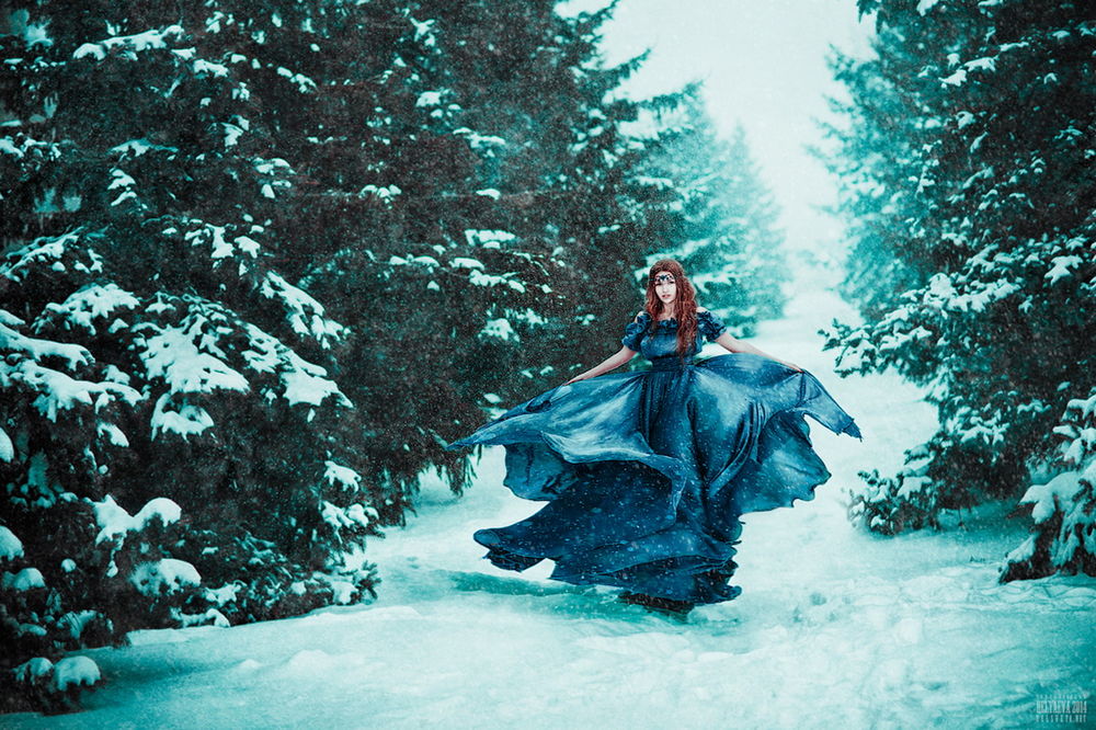 Обои для рабочего стола Рыжеволосая, стройная девушка в пышном синем платье, стоящая на лесной, заснеженной дороге, автор Светлана Беляева